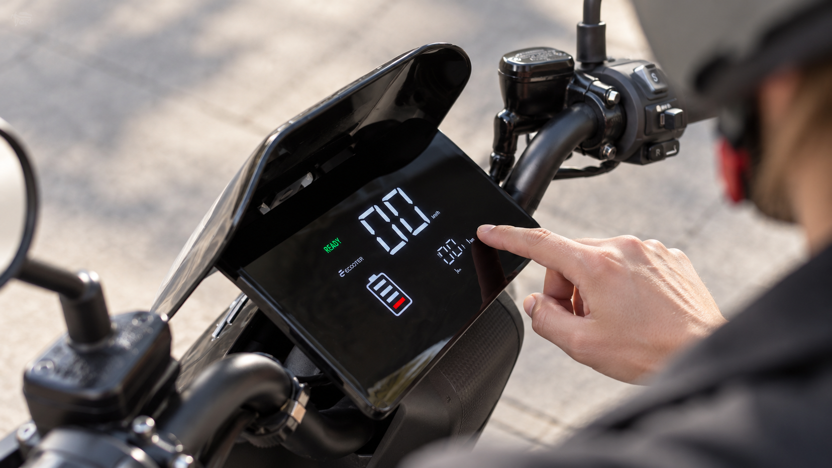 A commuter checks the range display on his e-scooter while standing on the side of the road in the city of Zurich.